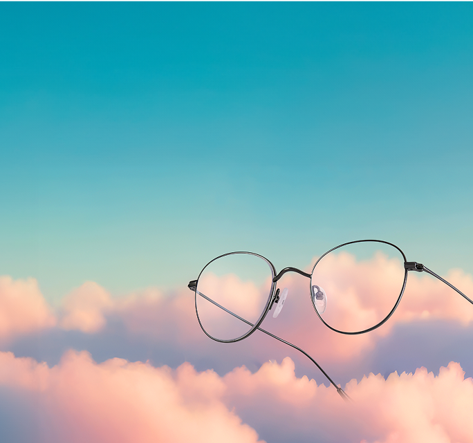 Round titanium glasses float on a background of pink clouds and blue sky.