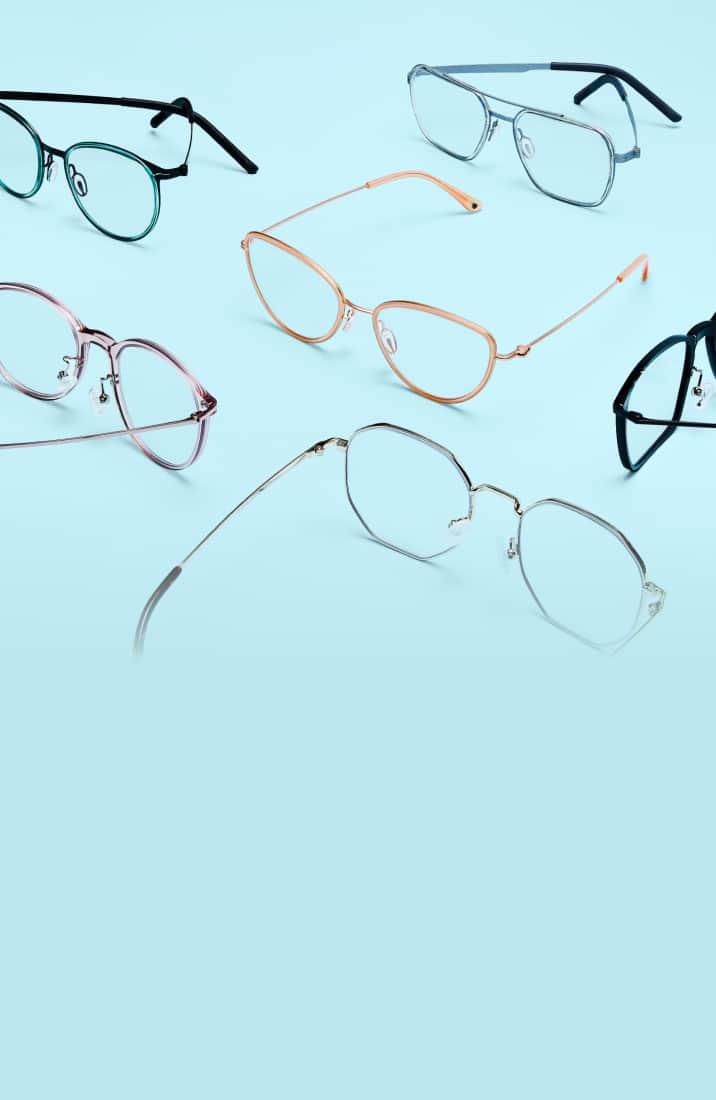 An array of lightweight eyeglasses with thin, colorful frames—including translucent pink, teal, gold, and metallic geometric styles—arranged neatly across a solid light blue background.