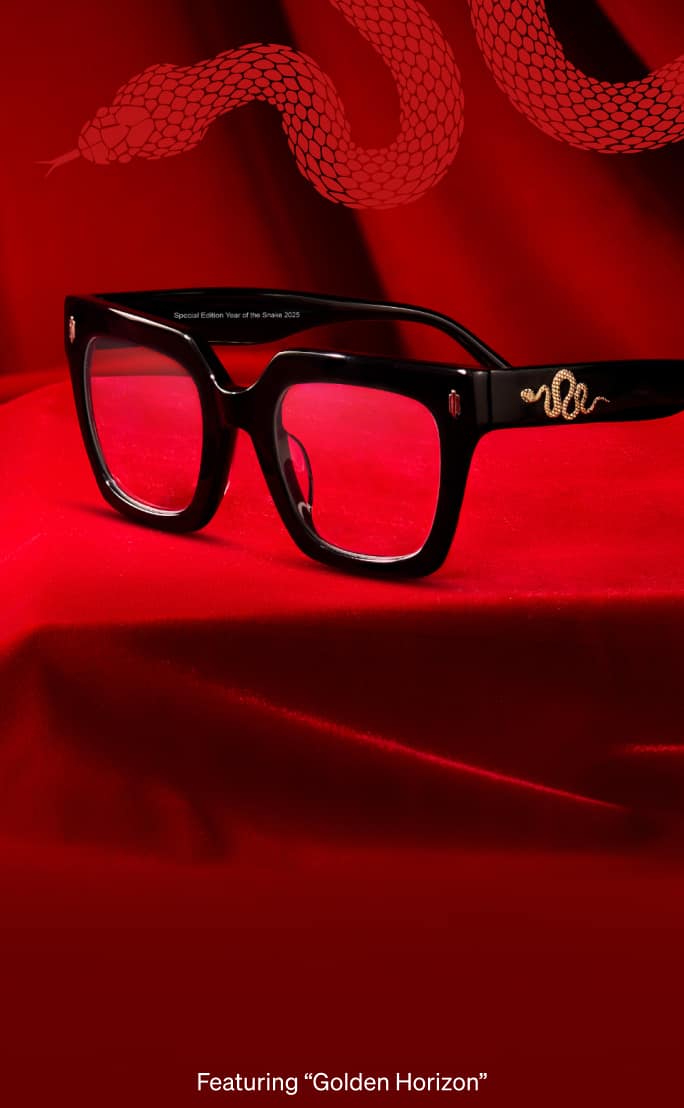  A pair of black glasses with gold snake details rests on vibrant red fabric. Beside it, a textured gold snake accessory sparkles under warm lighting.