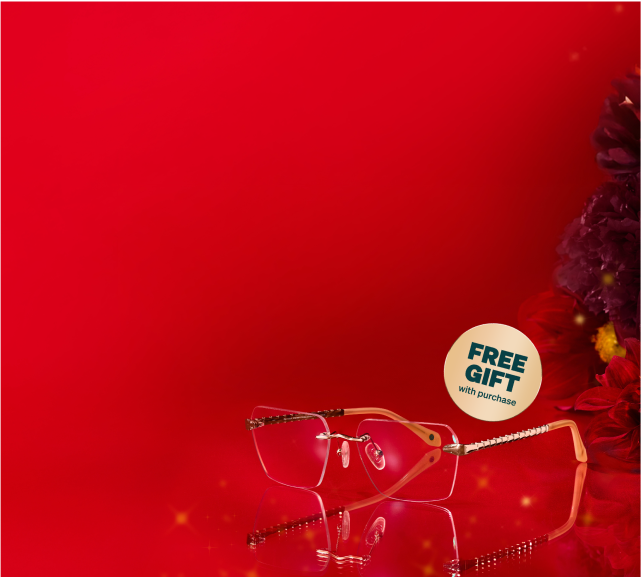 Rimless glasses with gold-toned frames and intricate detailing on the arms, on a red background with flowers and 'Free Gift' label.