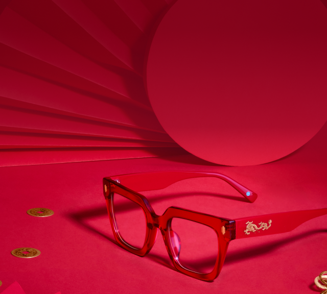 Square red glasses with a gold dragon inlay on the temple, on a red background.