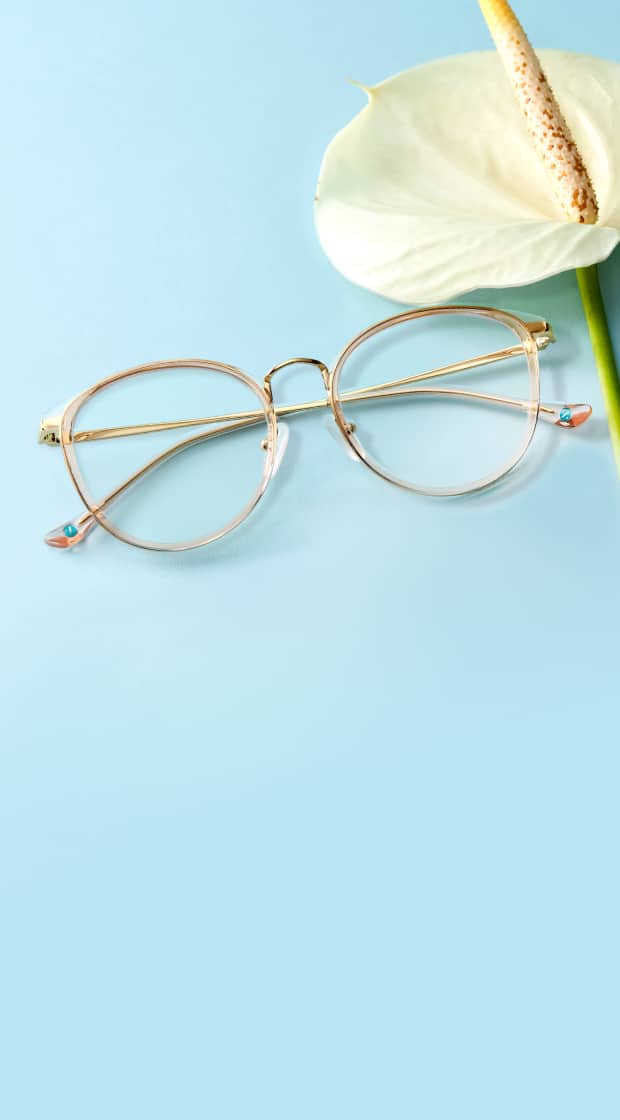 Round transparent and gold Zenni glasses on blue surface with a white lily.