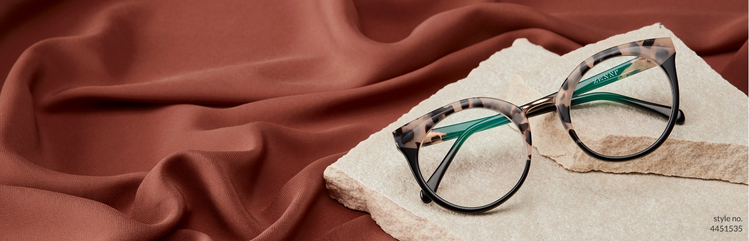Women’s new arrivals. Set your sights on this season’s hottest new eyewear. Image of Zenni cat-eye glasses #4451535 set atop a pile of sheet rock, in front of a warm brown background.