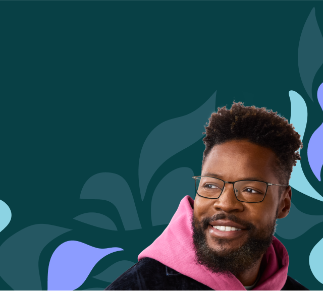 A man with curly hair and a beard wears black rectangular glasses style no. 1303412, a pink hoodie, and a black corduroy jacket. He smiles against a light blue background with abstract teal and lavender shapes.