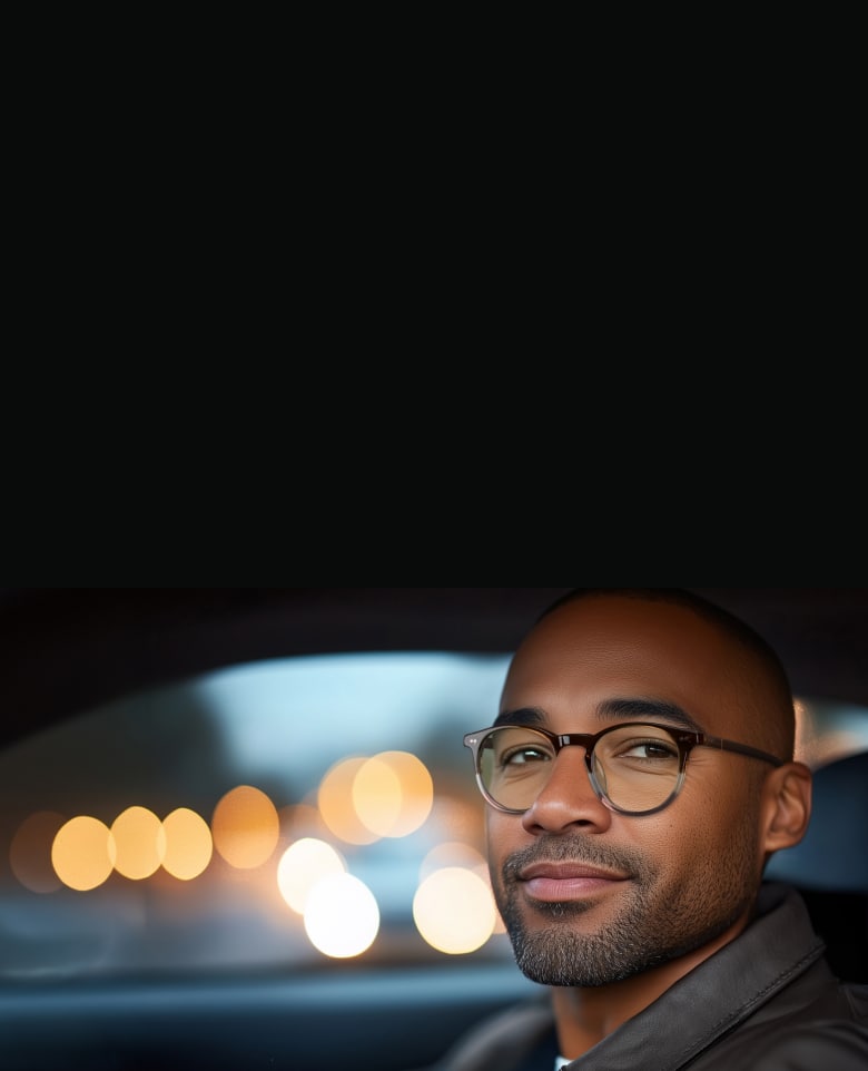 Person wearing Zenni night driving glasses, looking confident while driving at night with a clear view of the road.