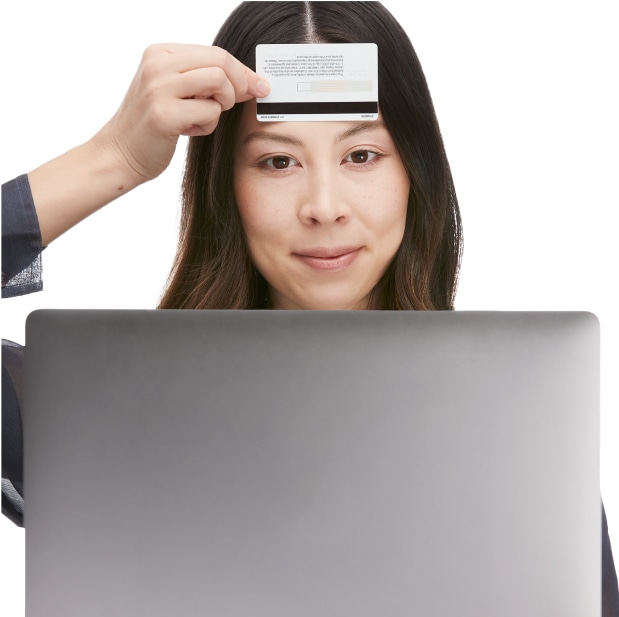 A woman holding a standard ID card against her forehead, taking a picture using the PD measuring tool on the laptop.