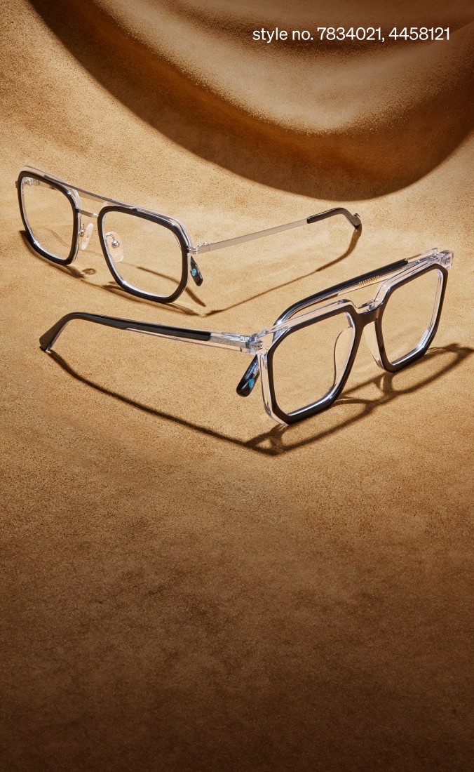 Two aviator eyeglasses rest on a textured tan surface, one with a black frame and silver temples, the other transparent with black accents. Style numbers 7834021 and 4458121.