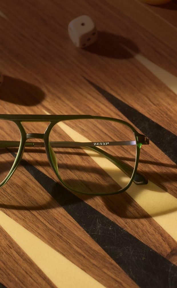Close-up of a pair of green-framed Zenni Progressive glasses lying on a wooden backgammon board.