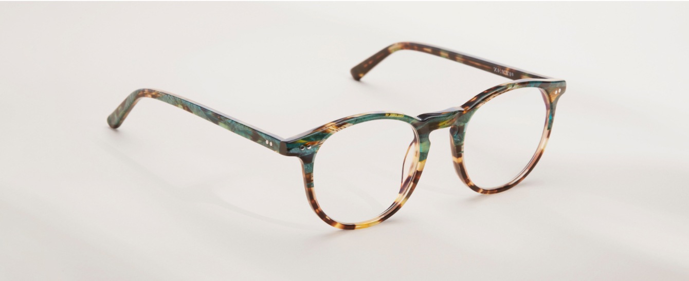 Simple grey background with the green tortoiseshell round Skyline glasses.