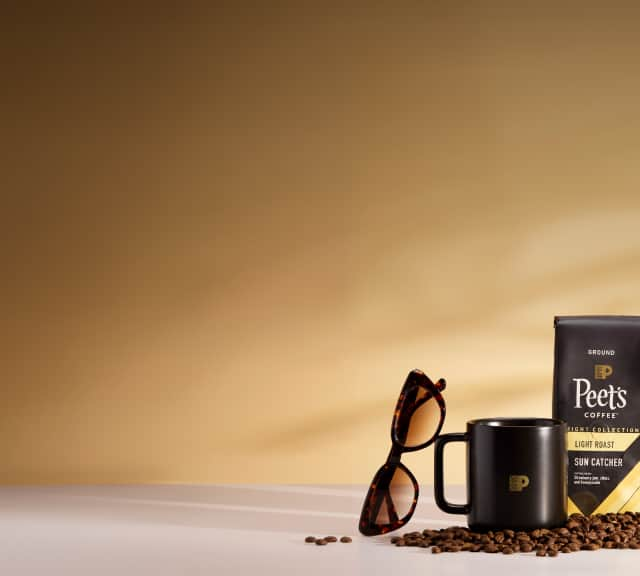 Image features two bags of Peet's Coffee, a black coffee mug, tortoiseshell sunglasses, and beige square sunglasses, all surrounded by coffee beans.