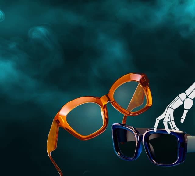 Orange and blue glasses against a misty, dark background with a skeleton hand, reinforcing the spooky atmosphere.