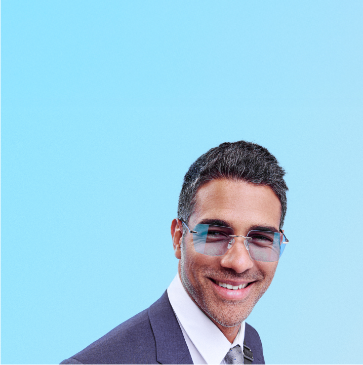 Man in a suit looking directly at the camera, wearing Zenni rimless glasses.