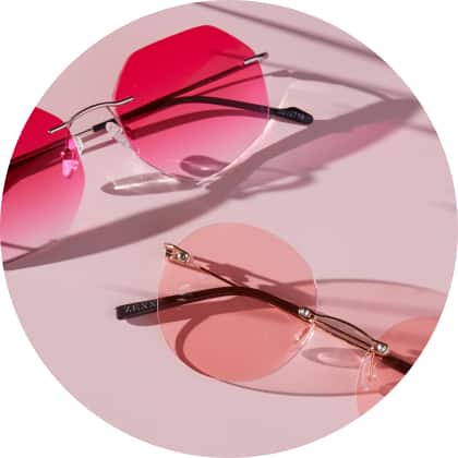 Zenni rimless glasses #3212719 lens shape #441 in pink gradient tint and #322114 lens shape #444 in rose fashion tint against a pink background.