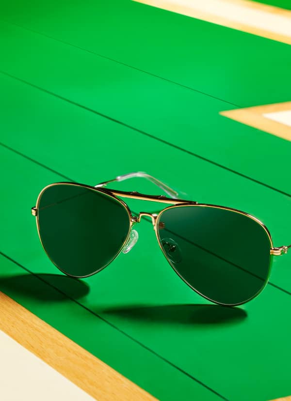 Zenni aviator sunglasses on wood parquet basketball court, titled 'Vision Drives the Game.' Call to View product.