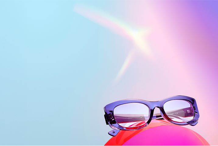 Purple eyeglasses on a red balloon with a blue and pink gradient background.