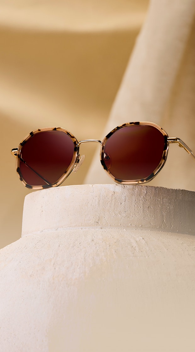 Geometric tortoiseshell Zenni glasses with brown lenses, on a beige stone background.