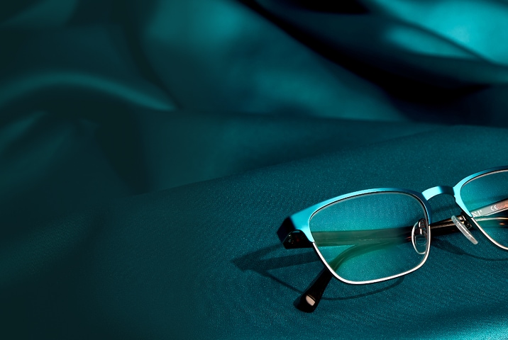 Teal browline Zenni glasses on a teal satin background.