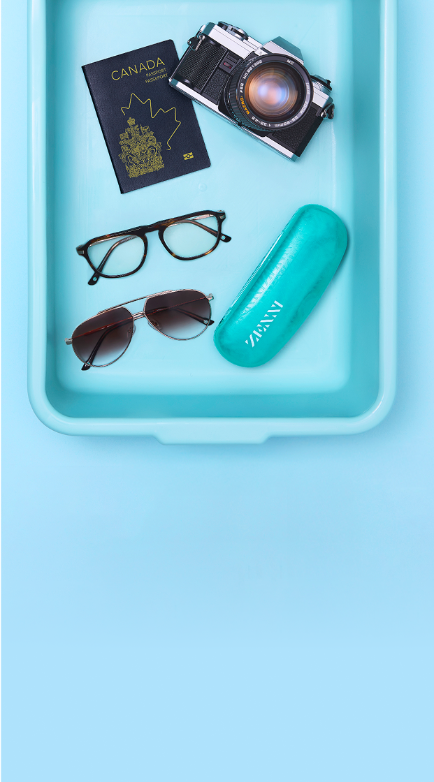 A security screening tray containing a pair of metal aviator sunglasses and a pair of tortoiseshell eyeglasses, a US passport, a Zenni glasses case, and a vintage film camera.