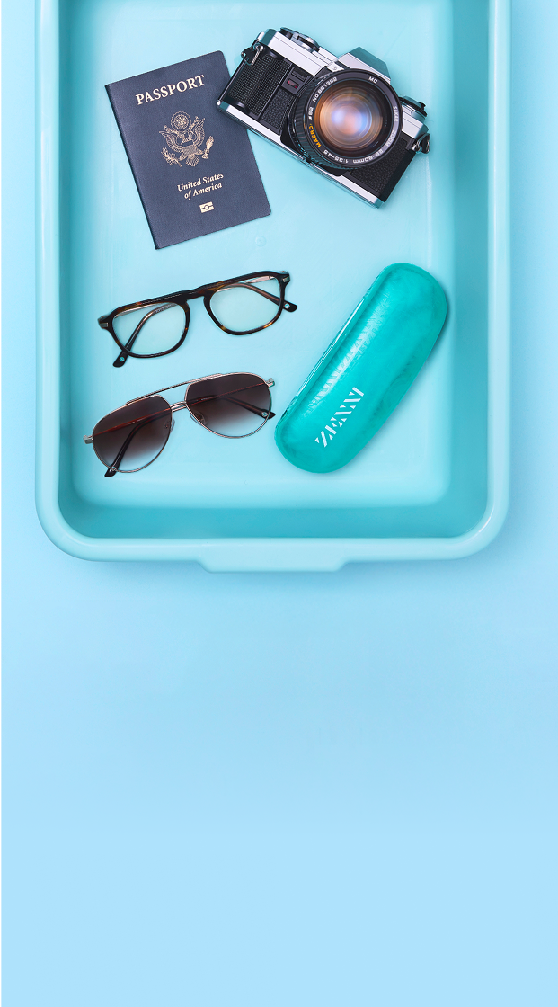 A security screening tray containing a pair of metal aviator sunglasses and a pair of tortoiseshell eyeglasses, a US passport, a Zenni glasses case, and a vintage film camera.