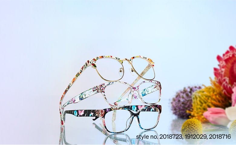 Three floral-patterned eyeglasses style no. 2018723, 1912029, 2018716, stacked diagonally on a gradient background with flowers on the side.
