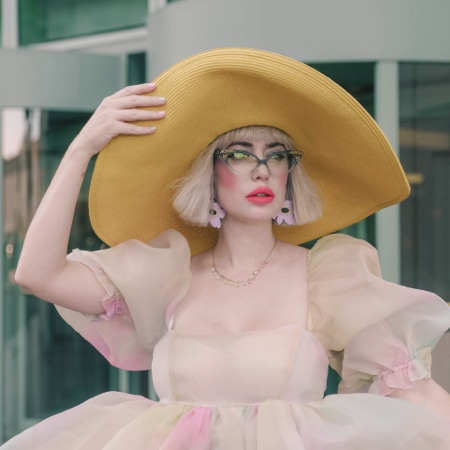 Amy Roiland wearing zenni cat-eye glasses #187616 in front of a modern building.