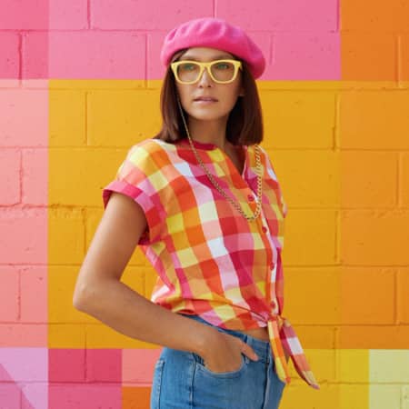 Ania Boniecka wearing Zenni square glasses #124122 against a brick wall painted in a variety of bright colors.