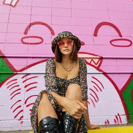 Ania Boniecka wearing zenni premium cat-eye sunglasses #1110919 in front of a pink-graffitied building. 