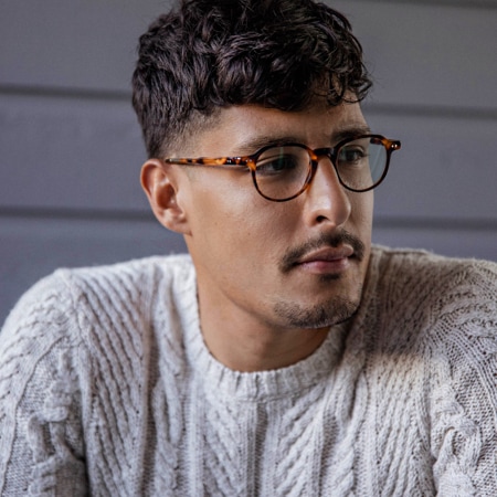 Carlos Roberto wearing Zenni Escape round glasses #4430925 in front of a grey wall background.