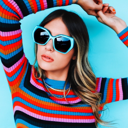 Kalianna Carpenter wearing zenni mulholland geometric sunglasses #112624 in front of an aqua blue background.