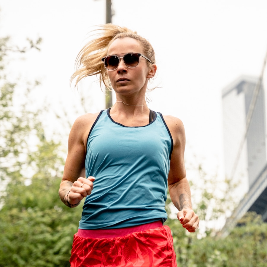 Image of a runner wearing red shorts, a blue top, and round sunglasses.