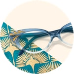Zenni cat-eye glasses #187616 on a cream-colored background with gold fan-patterned accents.