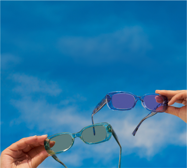 Translucent glasses with fashion tints are held up with blue sky as background.