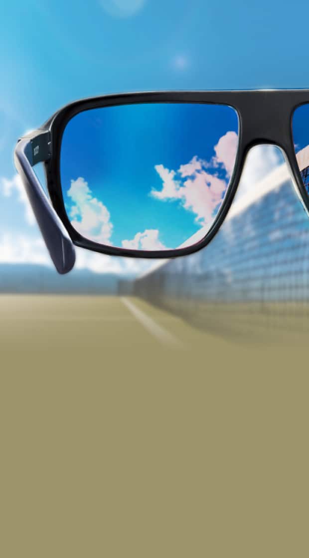 A sporty black frame with blue mirrored lenses reflects a tennis court scene. Style no. 1144021.