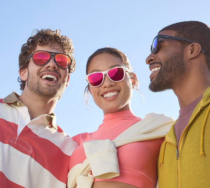 Two stylishly dressed men and a woman wearing various styles of Zenni sports sunglasses with mirror tint lenses. Blue sky background.
