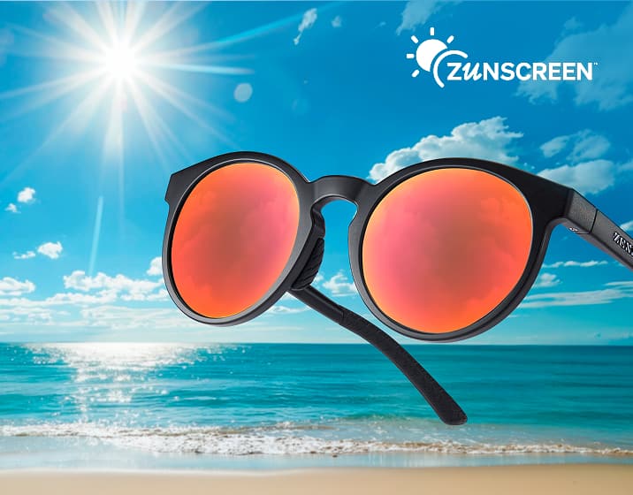 Matte black round sunglasses with vibrant red mirrored lenses floating over a sunny beach and ocean background under a white "Zunscreen" logo.