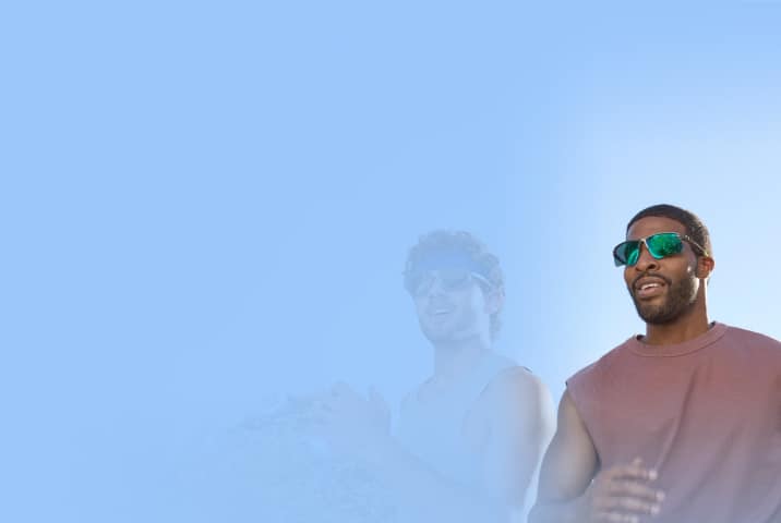 Two men jogging on a trail. One is wearing gray sports sunglasses with gray lenses. The other is wearing silver half-rim sports sunglasses with green mirror lenses.