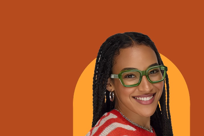 Smiling woman with braided hair wearing bold translucent green square eyeglasses and a red and white striped top against a pink arch on a purple background.