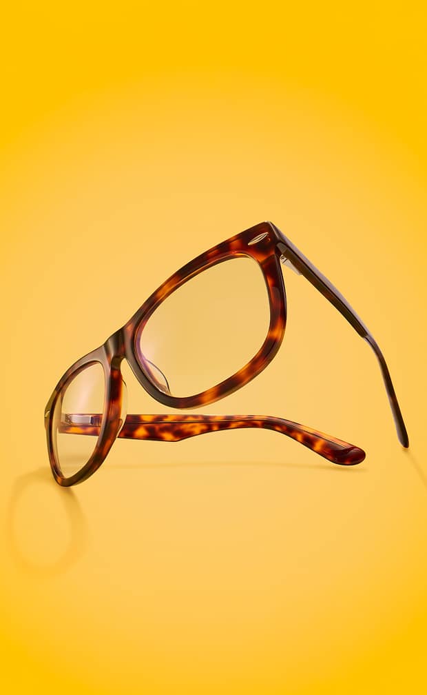 A pair of square tortoiseshell glasses floating at an angle against a solid bright yellow background.