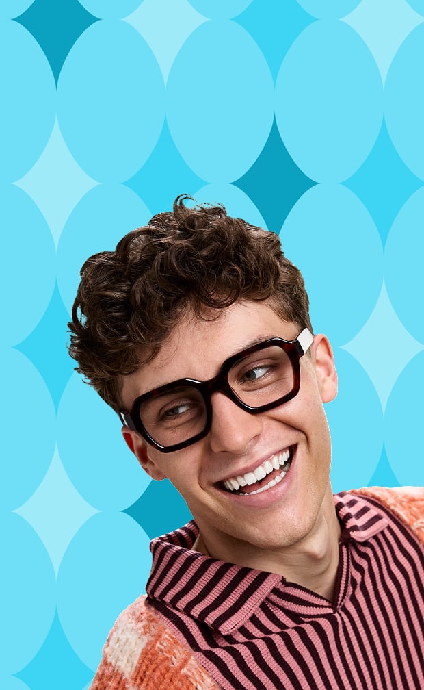 Man in bold square Zenni black glasses and a colorful striped sweater with an argyle blue background.