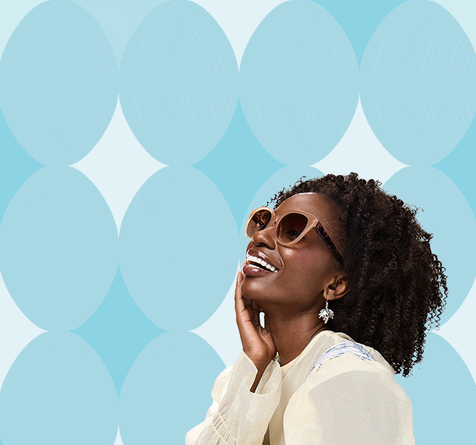 Three smiling people wearing trendy glasses pose in front of a blue patterned background — one with pink round sunglasses and white hair bows, another in dark square frames, and a third in oversized beige sunglasses with curly hair.