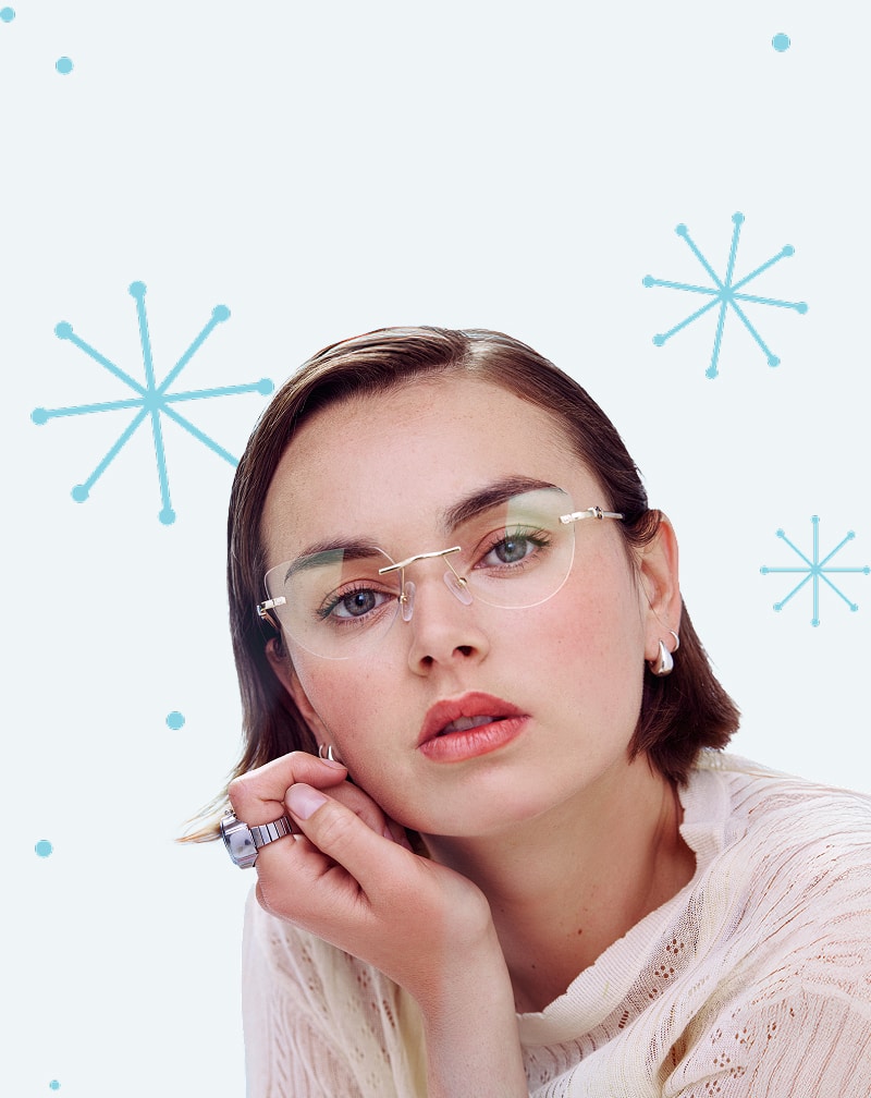 Woman with side-part dark hair wearing Zenni rimless glasses against a pale blue background with abstract snowflake shapes.