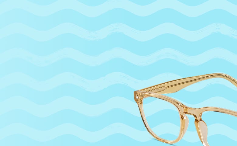 A pair of translucent amber eyeglasses sits against a light blue wavy background, creating a bright, summery feel.