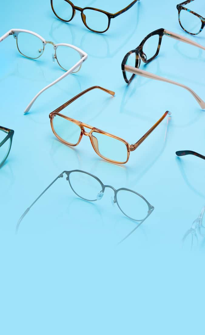 A collection of various eyeglass frames arranged on a smooth, light blue surface.