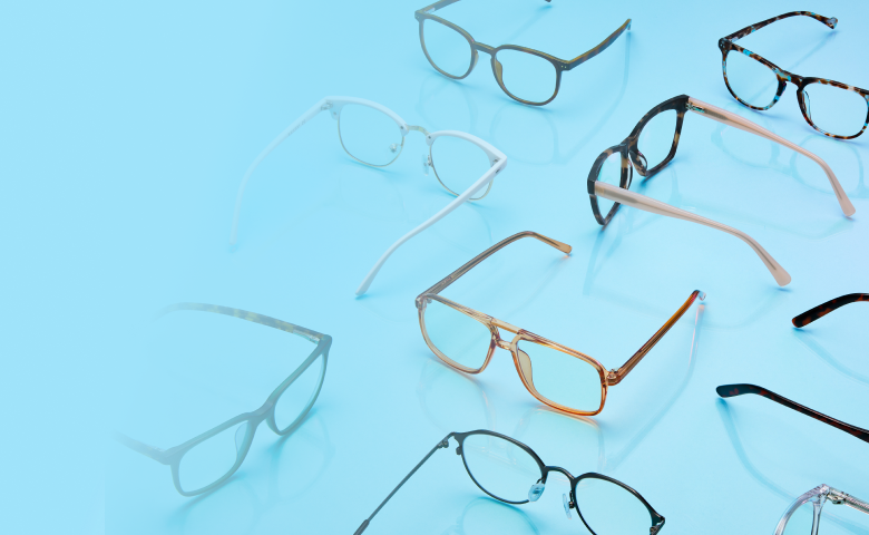 A collection of various eyeglass frames arranged on a smooth, light blue surface.