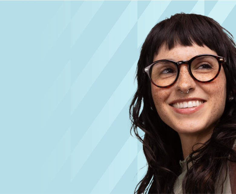 A smiling woman with wavy hair wearing chic frames a brown tortoiseshell color.