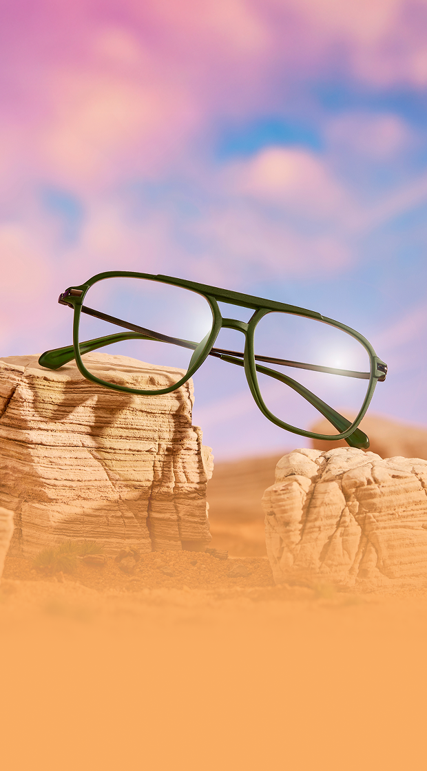 Green full rim plastic aviator glasses in a dessert sunset miniature diorama.