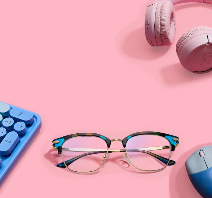 Teal and tortoiseshell browline glasses on a pink surface with a blue keypad, mouse, and pink headphones.