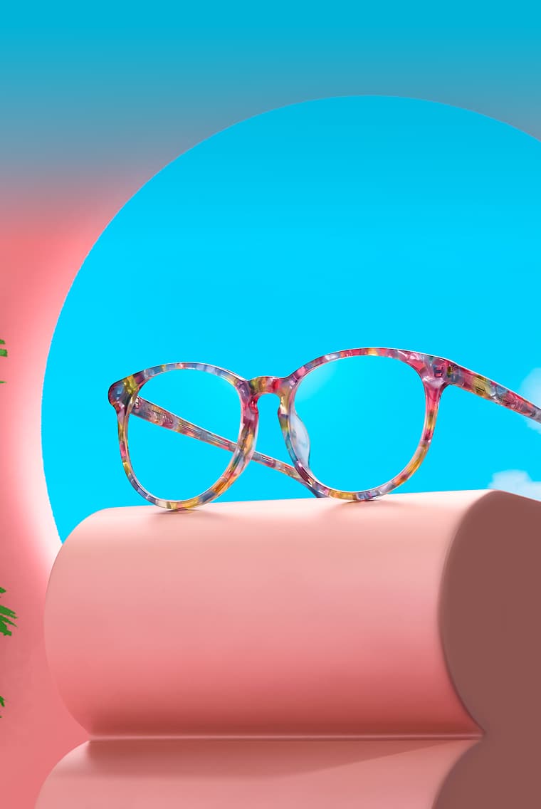 Zenni glasses in colorful round frames displayed on a pink riser with a sky blue background
