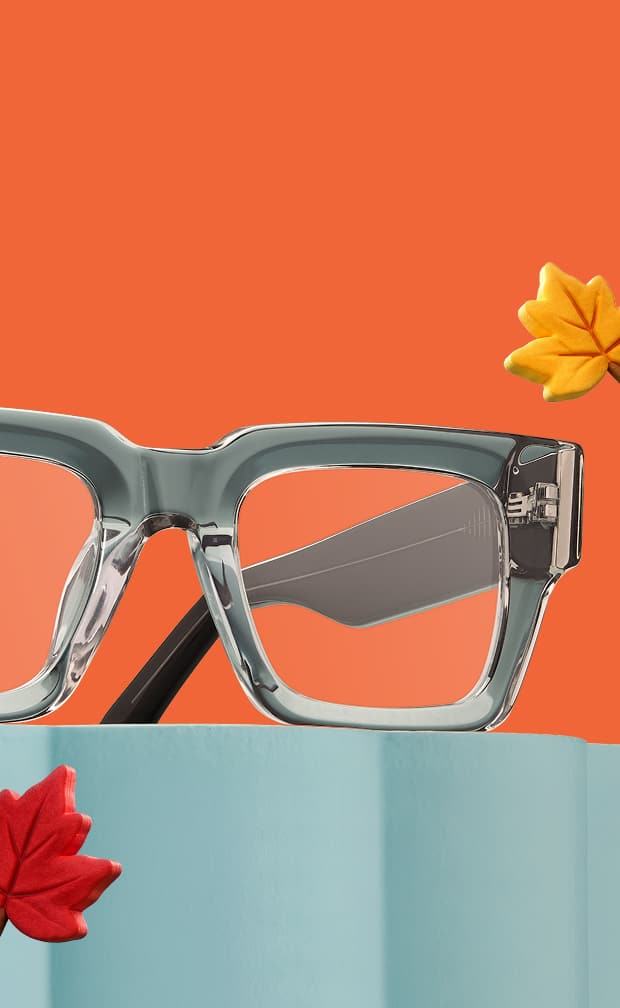 Lunettes carrées en gris translucide posées sur un piédestal bleu clair entouré de feuilles d'automne rouges et jaunes sur fond orange.