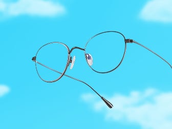 Zenni glasses in thin black round metal frames with clear lenses against a blue sky background